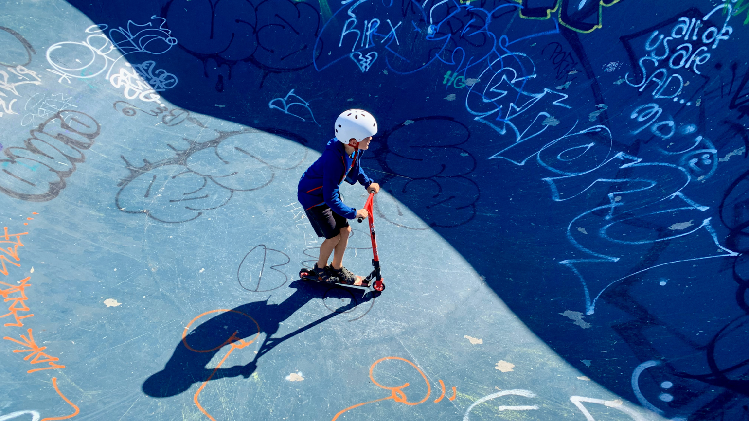 A boy with helmet rides a scooter