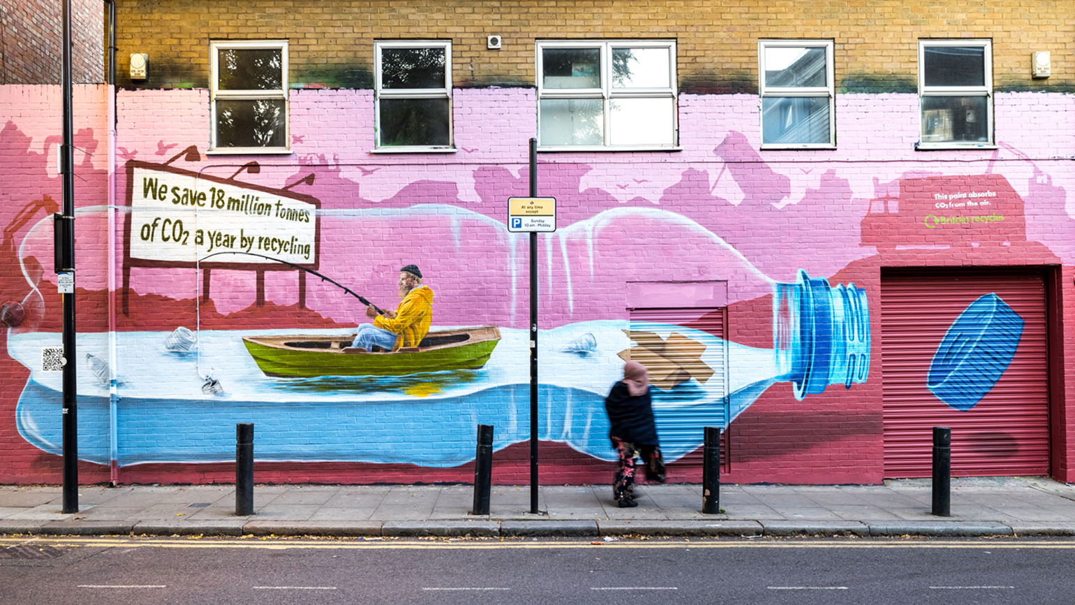 A face-fronted view of the graffiti of a man goes fishing inside a plastic bottle