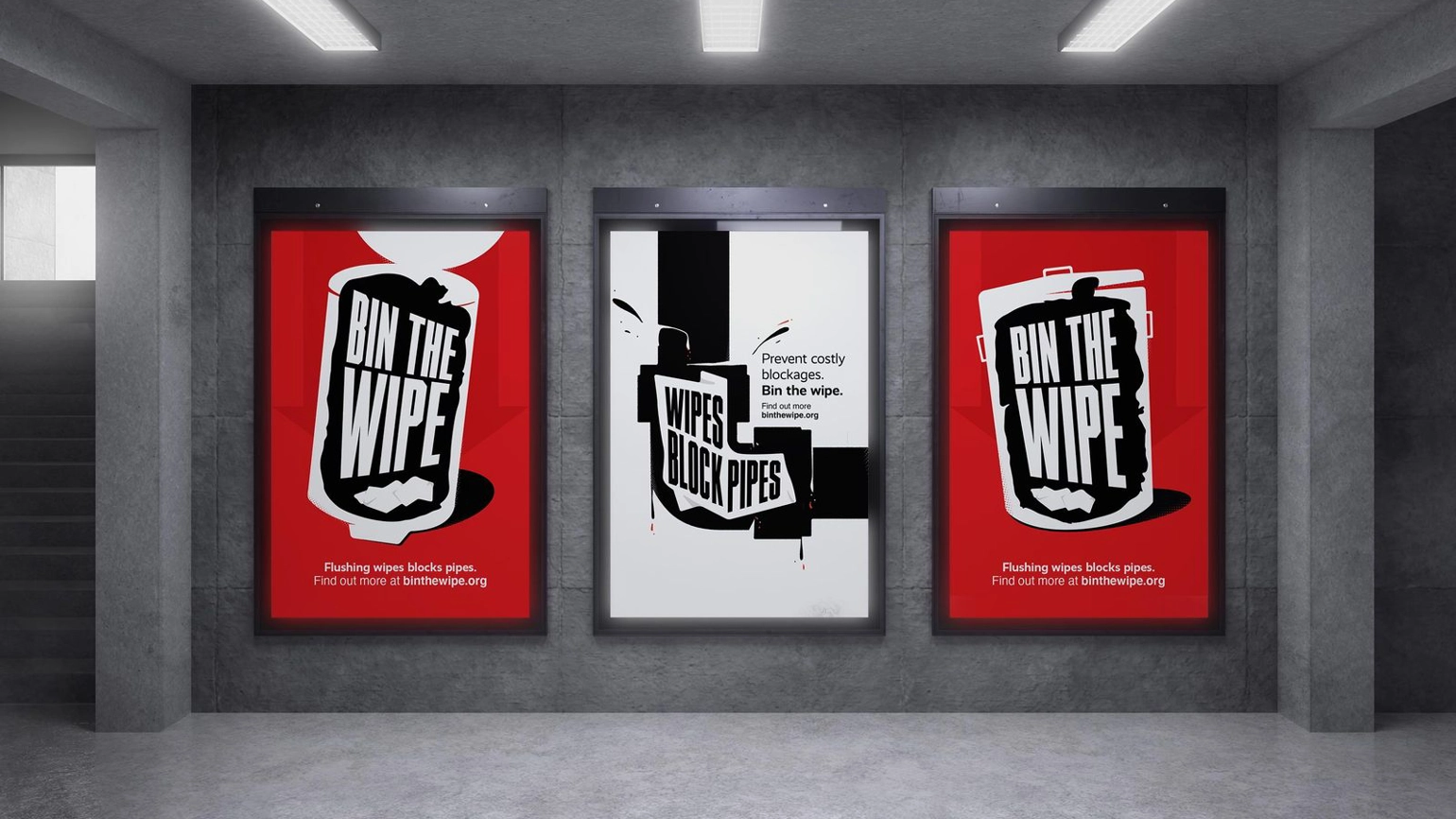 two red posters 'Bin the wipes' & one white 'wipes block pipes' sit next to each other on a grey wall under three white lights